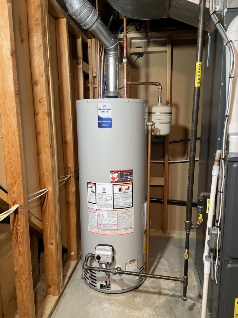 A white water heater installed in a basement with exposed wooden beams.